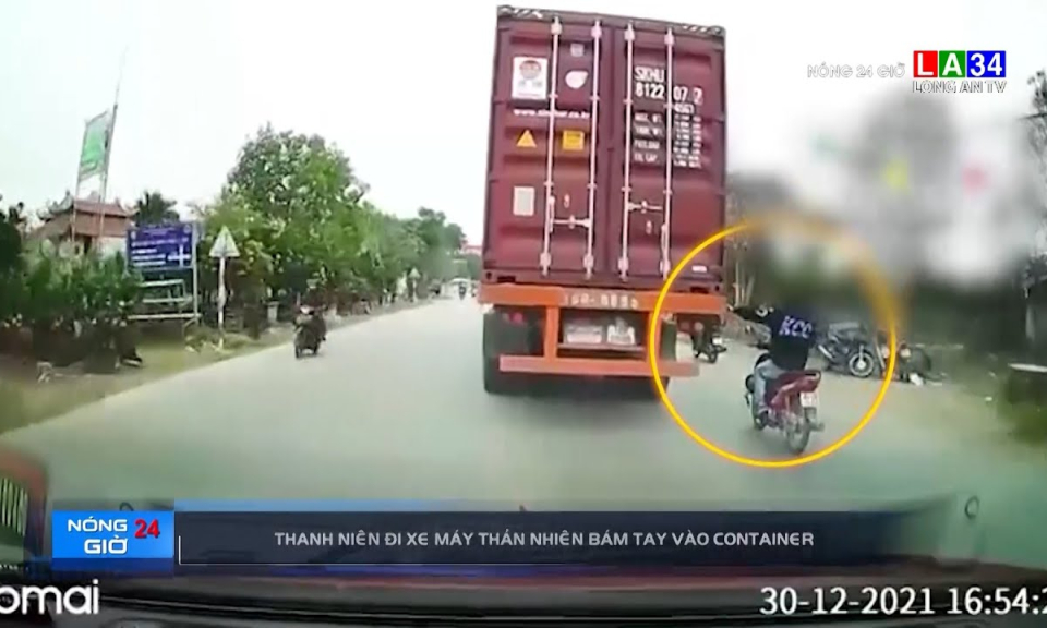 Thanh niên đi xe máy thản nhiên bám tay vào container