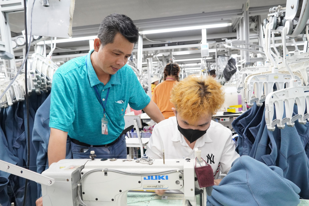 Anh Lê Quốc Khanh (Công ty TNHH Texray Việt Nam (TP.Tân An), đứng) hướng dẫn, nhắc nhở công nhân, lao động thực hiện các quy trình bảo đảm an toàn, vệ sinh lao động khi làm việc