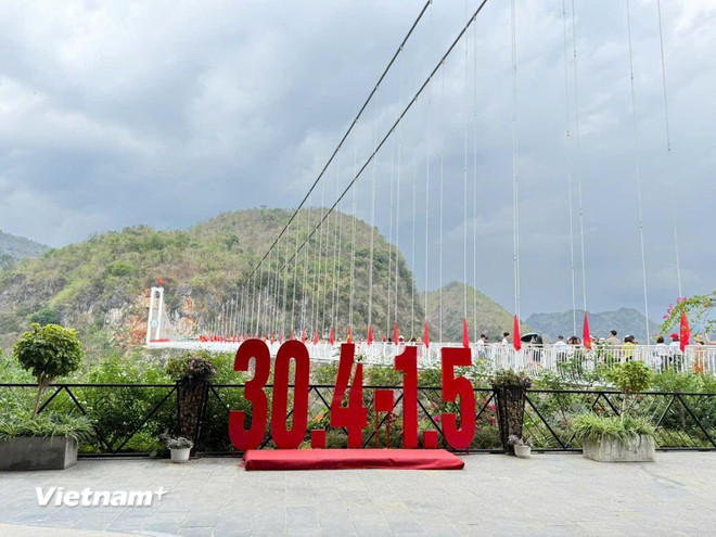 Cờ đỏ sao vàng được treo dọc cầu kính nhân kỷ niệm 50 năm giải phóng miền Nam thống nhất đất nước. (Ảnh: Vietnam+)