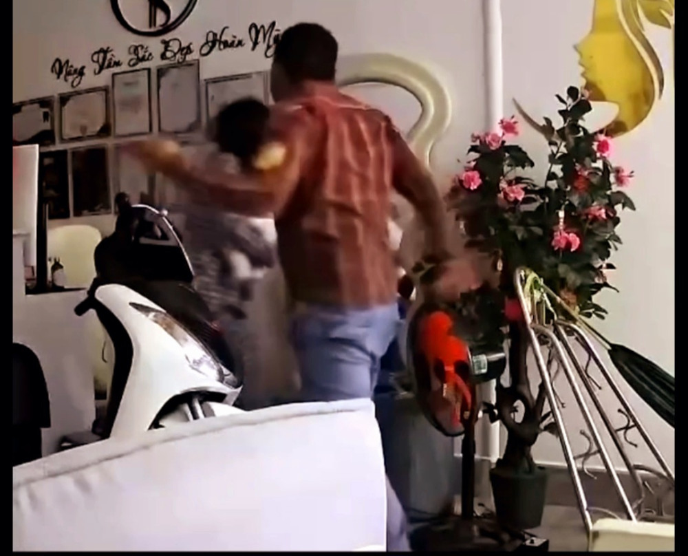 Người đàn ông đánh người vợ đang ôm con nhỏ (ảnh cắt từ clip)