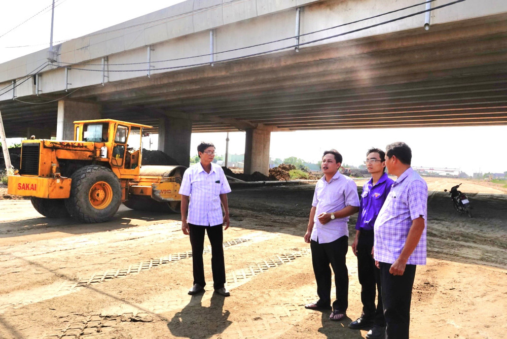 Người dân trước đó có đất trong diện giải phóng mặt bằng cùng cán bộ ở địa phương đứng trò chuyện trên nền đường Vành đai 3 TP.HCM đang được thi công