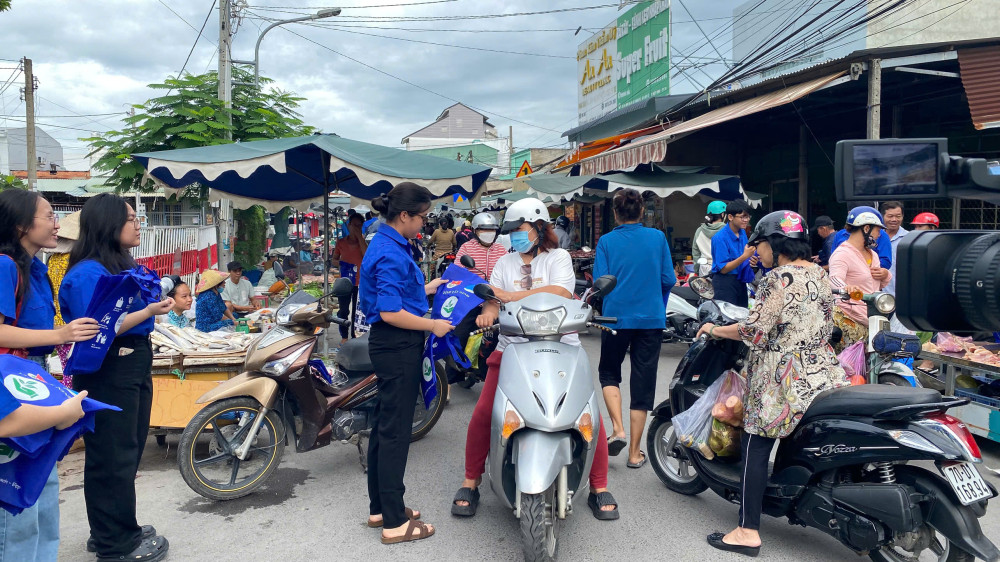 Các bạn đoàn viên tặng túi thân thiện với môi trường cho người dân