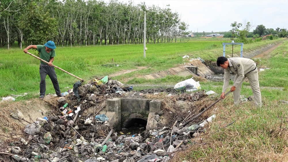 Ông Võ Văn Tài và anh Trần Tấn Tài đang vớt rác tại một cống ngang kênh N2A-7
