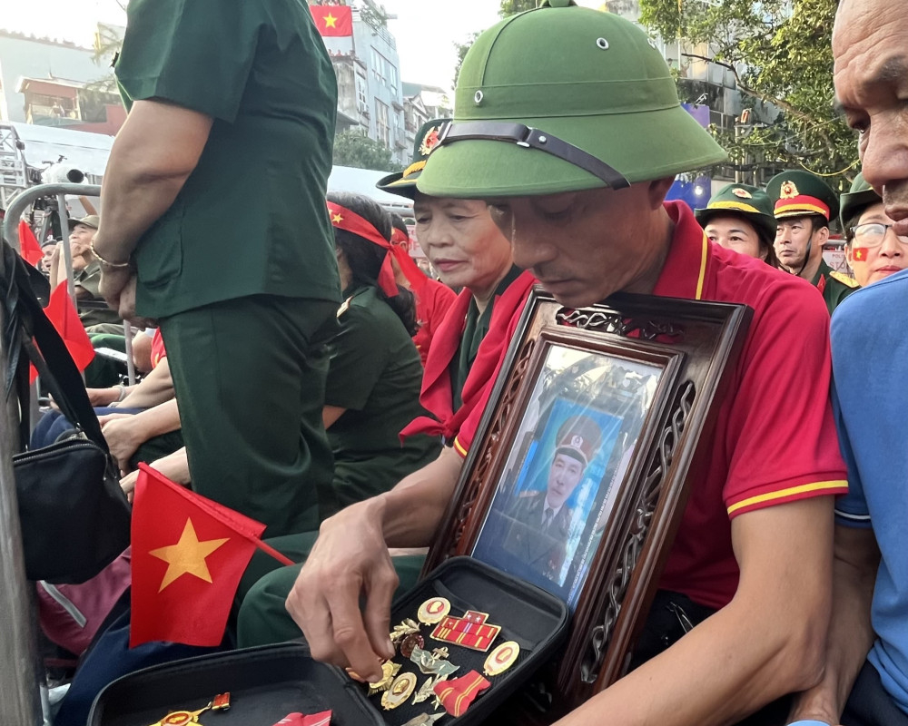 Anh Nguyễn Văn Mai mang theo di vật và di ảnh của bố là ông Nguyễn Minh Đức đến lễ diễu binh, diễu hành