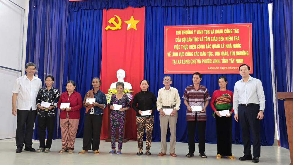 Ông Y Vinh Tơr (bìa trái) và ông Đoàn Trung Kiên (bìa phải) trao quà cho hộ người dân tộc thuộc hộ nghèo xã Long Chữ và xã Phước Vinh