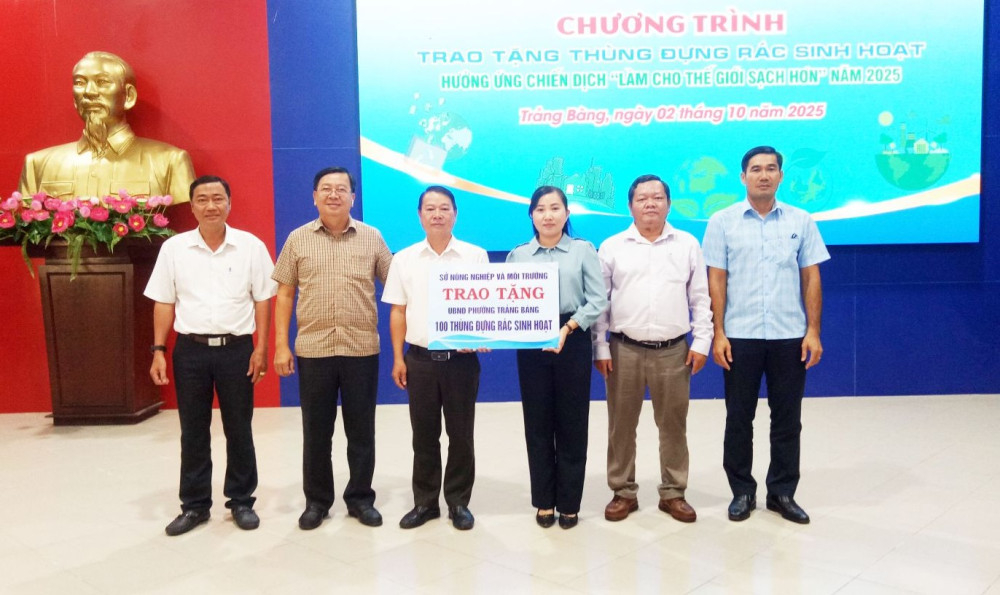 Phó Giám đốc Sở Nông nghiệp và Môi trường Trần Khắc Phục (thứ ba từ trái qua) trao bảng tượng trưng tặng 100 thùng đựng rác sinh hoạt cho lãnh đạo phường Trảng Bàng