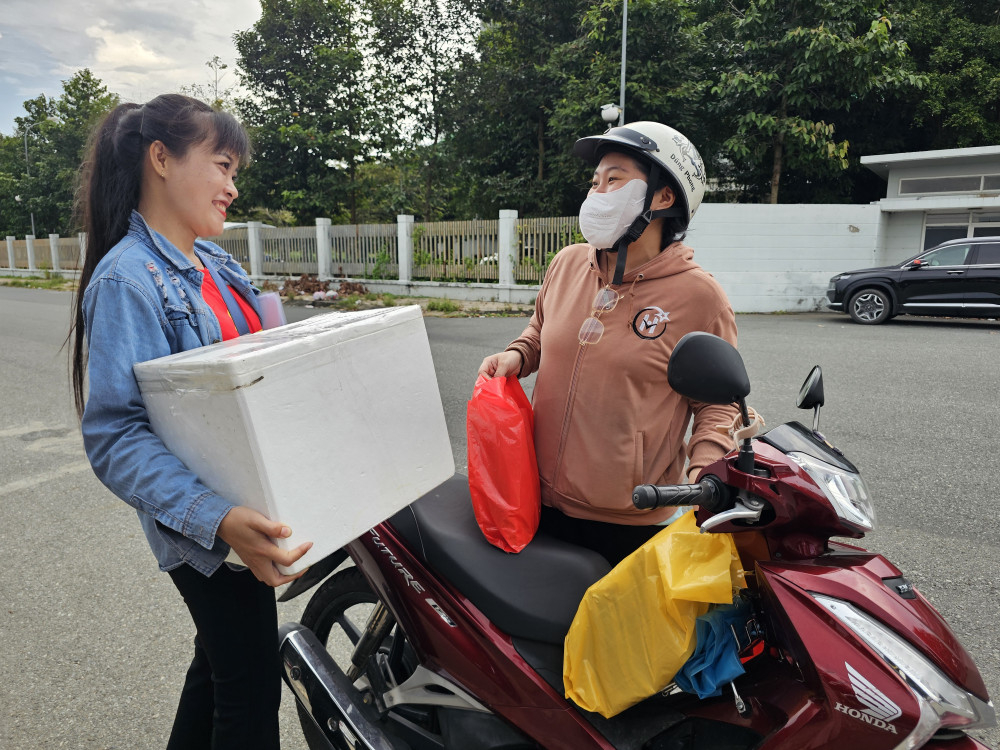 Chị Ngô Thị Trúc Ly (bên trái) nhận hàng hỗ trợ do chị Võ Thị Thủy Tiên mang tới trước khi đoàn khởi hành