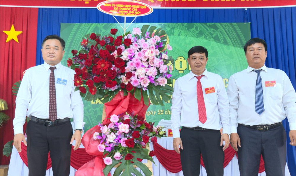 Đại diện Đảng ủy xã Phước Chỉ (bìa trái) tặng hoa chúc mừng Đại hội