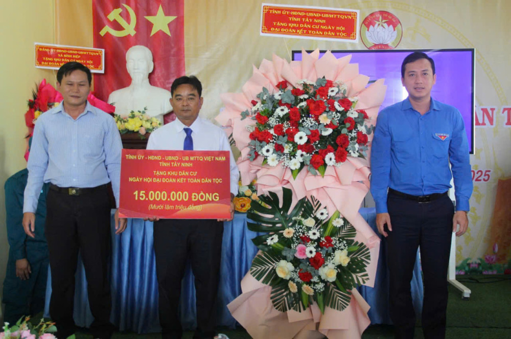 Phó Chủ tịch UBMTTQ Việt Nam, Bí thư Tỉnh Đoàn tỉnh Tây Ninh Trần Hải Phú (bìa phải) trao biểu trưng hỗ trợ 15 triệu đồng của Tỉnh ủy, HĐND, UBND, UBMTTQ Việt Nam tỉnh Tây Ninh cho đại diện khu dân cư ấp 2 tại Ngày hội