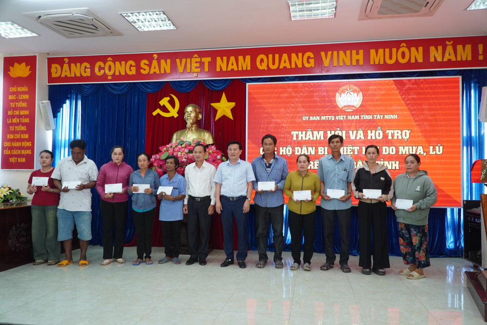 Phó Bí thư Tỉnh ủy, Chủ tịch UBMTTQ Việt Nam tỉnh Nguyễn Thanh Hải (thứ 6, từ trái qua) và lãnh đạo xã Mộc Hóa trao tiền hỗ trợ cho các hộ dân 