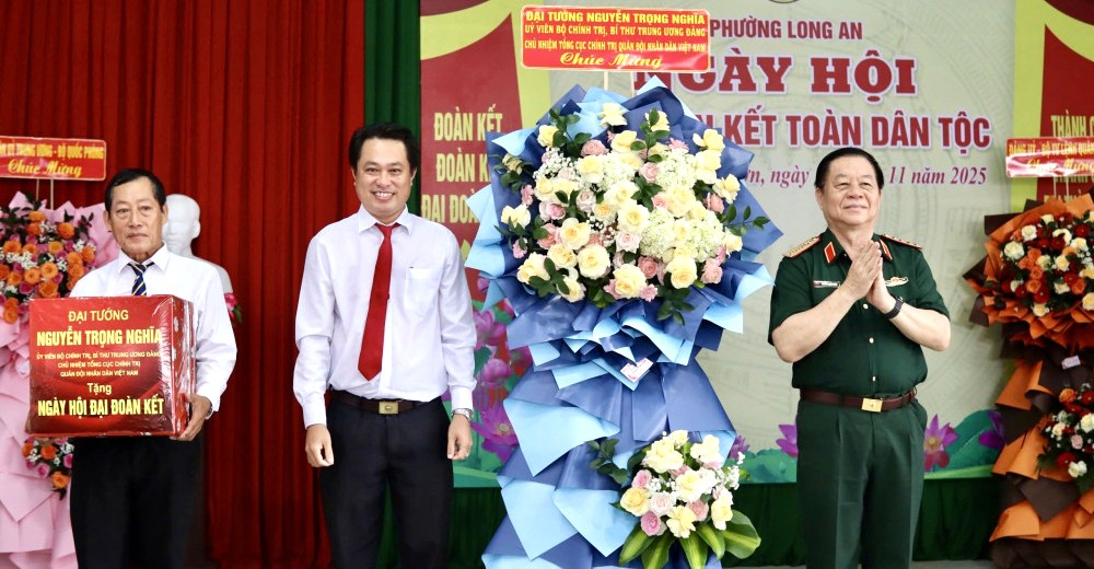 Đại tướng Nguyễn Trọng Nghĩa (bìa phải) trao lẵng hoa và quà của Quân ủy Trung ương, Bộ Quốc phòng tặng phường Long An, khu phố Phú Nhơn
