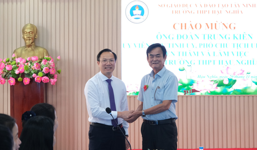 Ủy viên Ban Thường vụ Tỉnh ủy, Phó Chủ tịch UBND tỉnh Đoàn Trung Kiên (bên trái) gửi lời chúc mừng tốt đẹp đến Hiệu trưởng Trường THPT Hậu Nghĩa Trần Văn Truyến