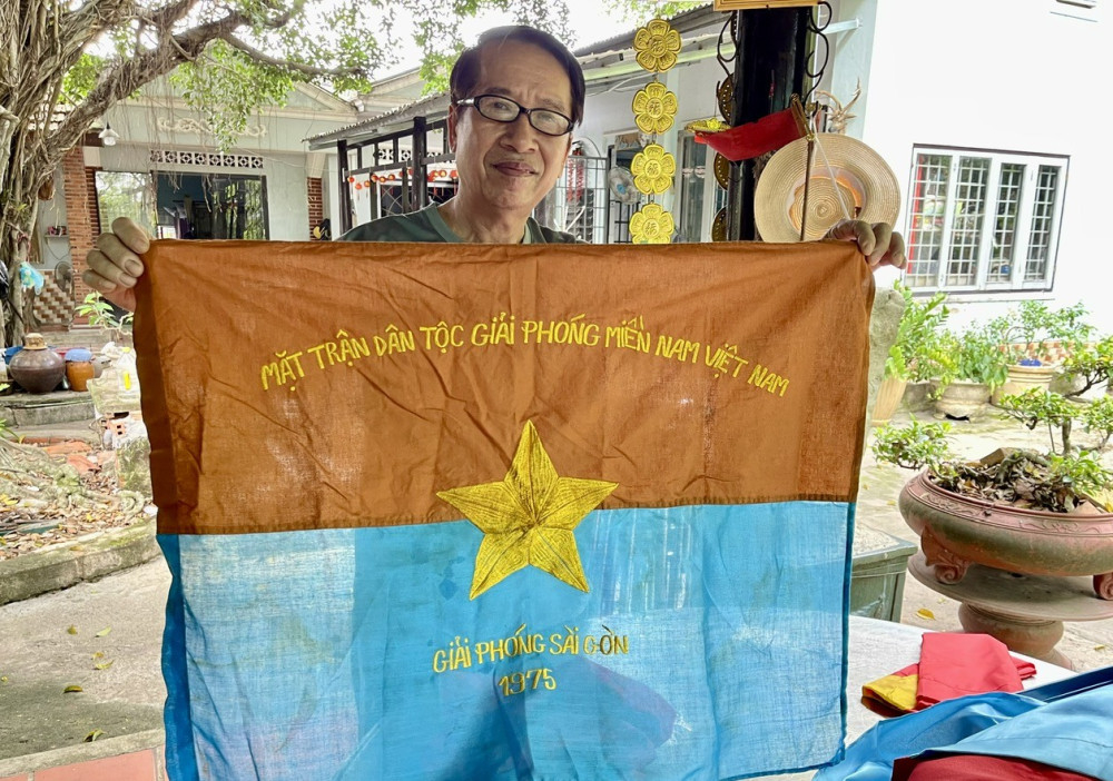Cựu chiến binh Trần Ngọc với lá cờ Mặt trận Dân tộc giải phóng miền Nam Việt Nam 
