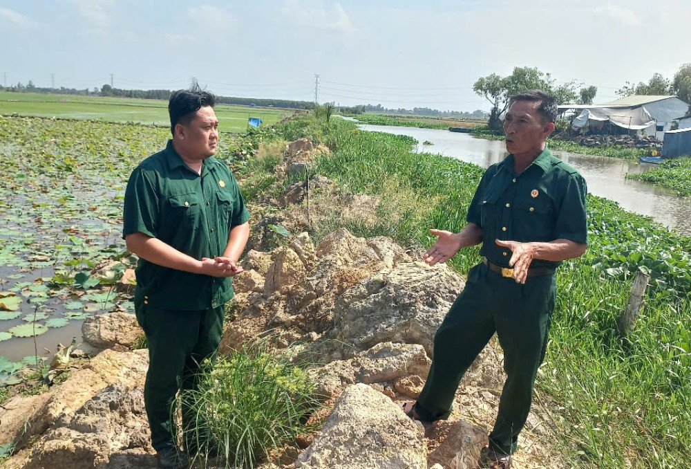 Cựu chiến binh Ngô Hồng Luôn (bên phải) tích cực tuyên truyền hội viên tự nguyện hiến đất xây dựng hệ thống đê bao phục vụ sản xuất