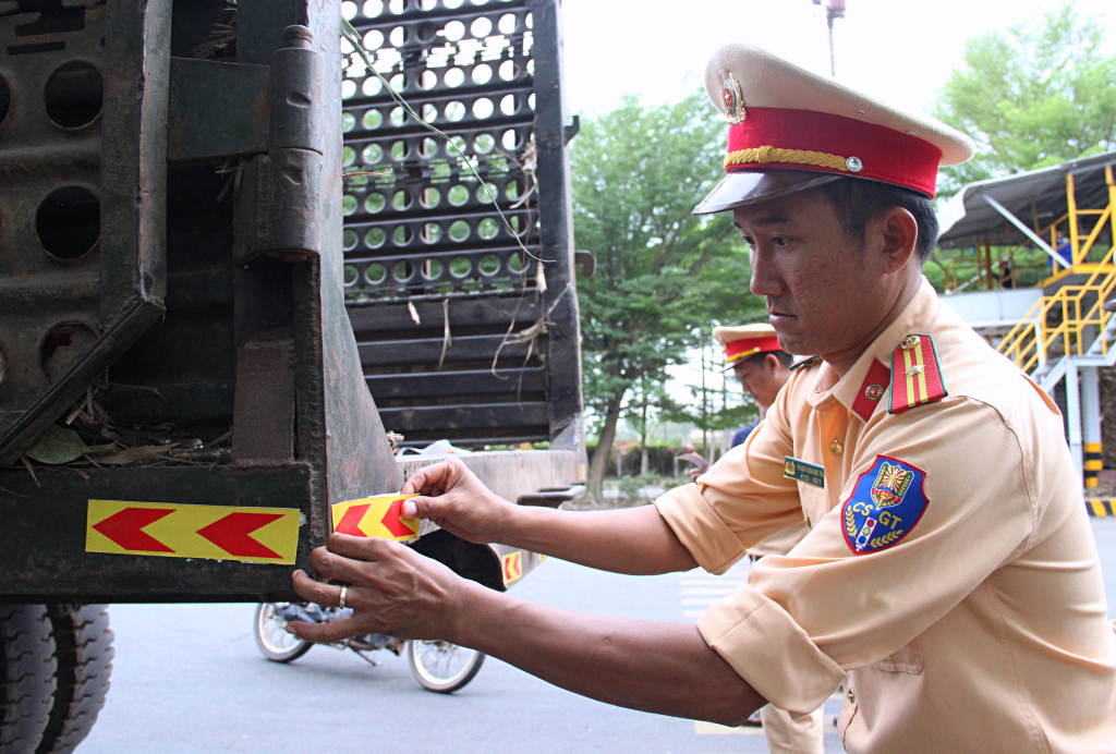 Cảnh sát giao thông dán phản quang cho xe vận chuyển mía